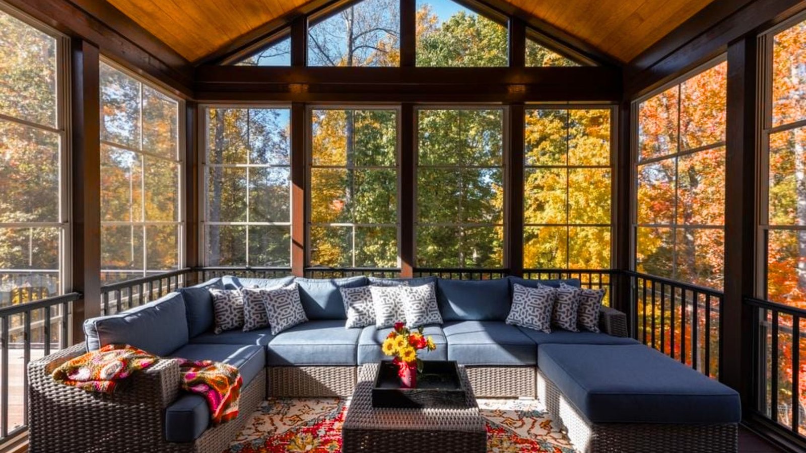 A screened porch featuring comfortable couches and a wicker table, creating a cozy outdoor living space.