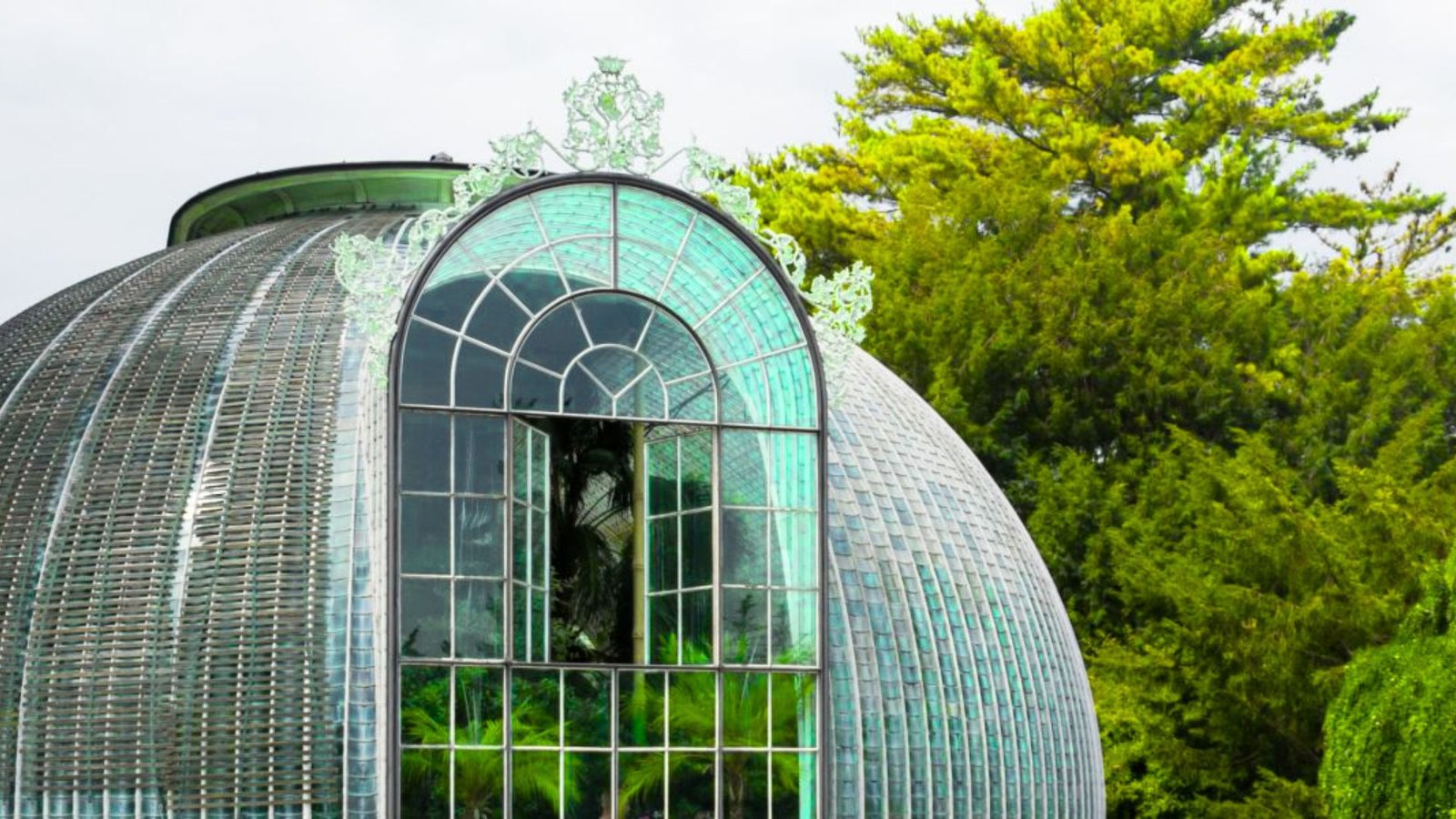 A glass dome structure with a green roof, surrounded by trees, illustrating the concept of a conservatory.