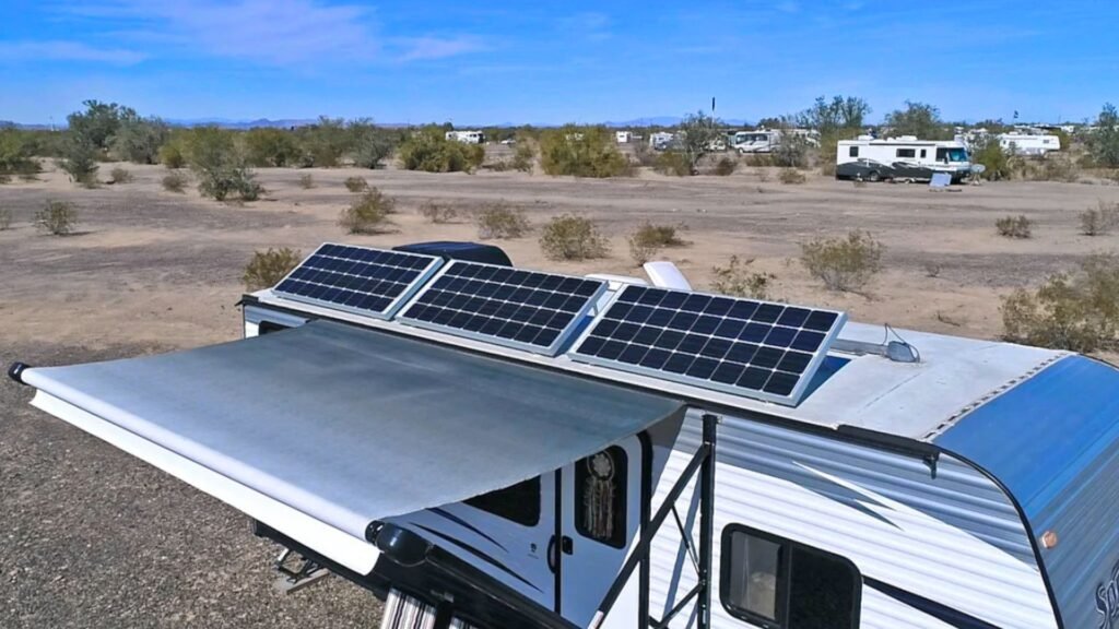 A solar panel mounted on an RV parked in a vast desert landscape under a clear blue sky.